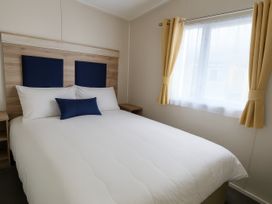 A bedroom with a bed and nightstand at Lyons Sunnysands Holiday Park - Holiday Accommodation 13733, Barmouth