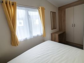 A bedroom with a bed and window at Lyons Sunnysands Holiday Park - Holiday Accommodation 13733, Barmouth