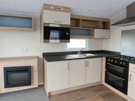 A kitchen with appliances and storage at Lyons Sunnysands Holiday Park - Holiday Accommodation 13733, Barmouth