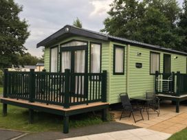 A holiday home with a deck and chairs at Hafan y Mor Haven - Holiday Accommodation 1444 Pwllheli