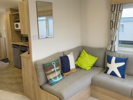 A living room with a sofa and kitchen unit at Reighton Sands Holiday Park - Holiday Accommodation 14875 in Filey