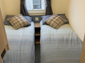 A bedroom with two single beds and a window at Reighton Sands Holiday Park - Holiday Accommodation 14875, Filey