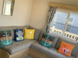 A living room with a couch and decorative pillows at Reighton Sands Holiday Park - Holiday Accommodation 14875, Filey