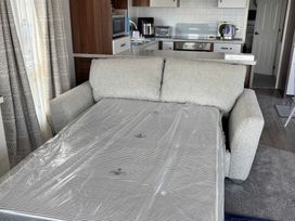 A sofa with kitchen appliances and curtains at Lydstep Beach - Holiday Accommodation 14896 in Tenby