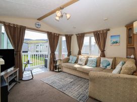 A living room with a sofa and television at Sunnysands in Talybont near Barmouth