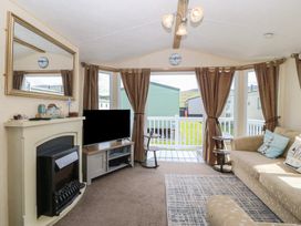 A living room with a fireplace and television at Sunnysands in Talybont near Barmouth