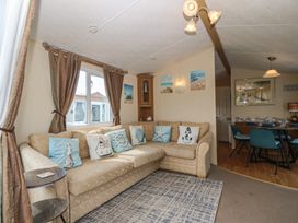 A living room with a sofa and dining area at Sunnysands in Talybont near Barmouth