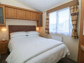A bedroom with a bed and wall-mounted cabinets at Sunnysands in Talybont near Barmouth
