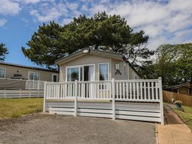 A cabin with a deck and trees at Pine Tree Lodge - Shorefield Country Park in Milford On Sea