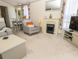 A living room with a sofa, armchair, and dining table at Pine Tree Lodge - Shorefield Country Park, Milford On Sea