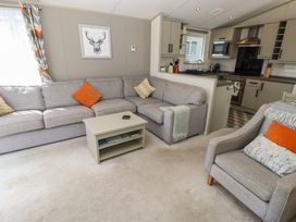 A living room with a sofa and kitchenette at Pine Tree Lodge - Shorefield Country Park in Milford On Sea