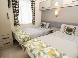 A bedroom with two beds and a bedside table at Pine Tree Lodge - Shorefield Country Park Milford On Sea