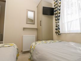 A bedroom with two beds and a television at Pine Tree Lodge - Shorefield Country Park, Milford On Sea