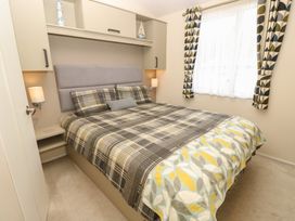 A bedroom with a double bed and nightstand at Pine Tree Lodge - Shorefield Country Park Milford On Sea