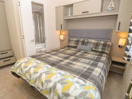 A bedroom with a bed and storage cabinet at Pine Tree Lodge - Shorefield Country Park, Milford On Sea