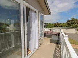 A balcony with a sofa and curtain at Pine Tree Lodge - Shorefield Country Park, Milford On Sea
