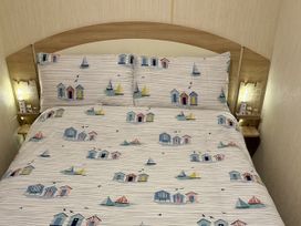 A bed with patterned bedding and bedside table at Thornwick Bay Holiday Village - Holiday Accommodation 15653 Bridlington