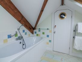 A bathroom with a bathtub and a door at Fastnet at Nonsuch House Kingswear, Devon