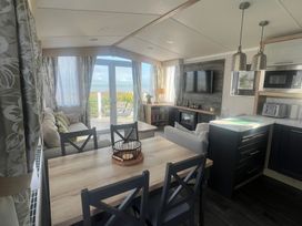 A living room with a sofa, dining area, and kitchen at Hafan y Mor Haven - Holiday Accommodation 16251, Pwllheli