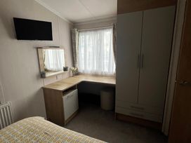 A bedroom with a desk and wardrobe at Hafan y Mor Haven - Holiday Accommodation 16251 Pwllheli