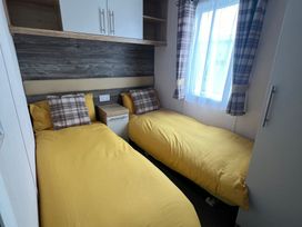 A bedroom with twin beds and a nightstand at Hafan y Mor Haven - Holiday Accommodation 16251 Pwllheli