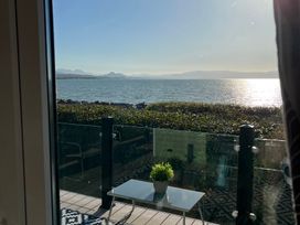 A balcony with a table and plant overlooking water at Hafan y Mor Haven - Holiday Accommodation 16251 Pwllheli