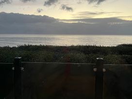 An ocean view with a glass fence and bushes at Hafan y Mor Haven - Holiday Accommodation 16251 Pwllheli