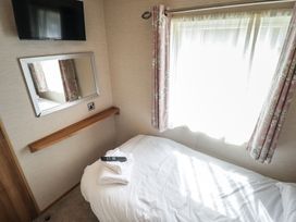 A bedroom with a bed, a TV mounted on the wall, and a mirror at Tattershall Lakes Country Park - Holiday Accommodation 16408 in Tattershall