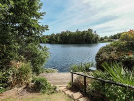 A view of water with a wooden deck and surrounding plants at Tattershall Lakes Country Park - Holiday Accommodation 16408 Tattershall