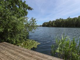 A view of water with a wooden deck and surrounding plants at Tattershall Lakes Country Park - Holiday Accommodation 16408, Tattershall