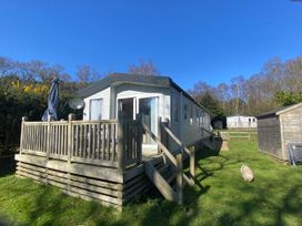 A caravan with a deck and umbrella at Kelling Heath Holiday Park - Holiday Accommodation 16498 Holt