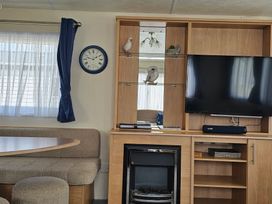 A living room with a television and a sofa at Hayling Island Holiday Park - Meadow Bay Villages - Holiday Accommodation 16626, Hayling Island
