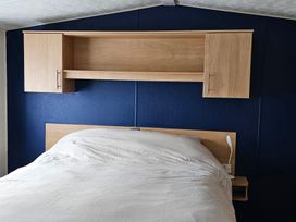 A bedroom with a bed and wall shelves at Hayling Island Holiday Park - Meadow Bay Villages - Holiday Accommodation 16626 Hayling Island