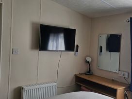 A bedroom with a television and a mirror at Hayling Island Holiday Park - Meadow Bay Villages - Holiday Accommodation 16626