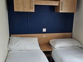 A bedroom with two single beds and a shelf at Hayling Island Holiday Park - Meadow Bay Villages - Holiday Accommodation 16626, Hayling Island
