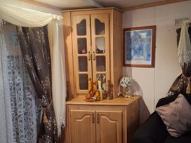 A sitting room with a cupboard and lamp at The Chase - Holiday Accommodation 1675 Ingoldmells