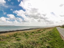 A shoreline with water and grass beside a road at WigBay Holiday Park - Holiday Accommodation 16774, Stranraer