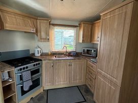 a kitchen with wooden cabinets and appliances at Coral Beach - Holiday Accommodation 16858 in Ingoldmells