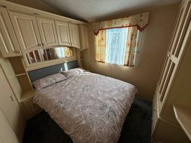 a bedroom with a double bed and patterned bedding at Coral Beach - Holiday Accommodation 16858 in Ingoldmells