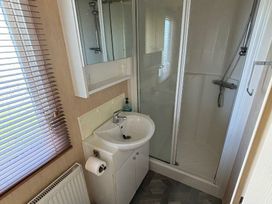 a small bathroom with a shower, sink, and mirror at Coral Beach - Holiday Accommodation 16858 in Ingoldmells