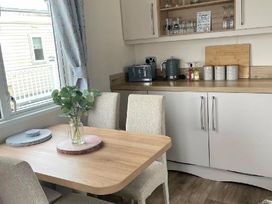 a dining area with a wooden table and chairs near a kitchenette at Quay West Holiday Park - Holiday Accommodation 16905 in New Quay
