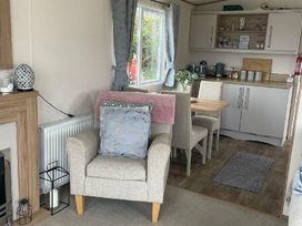 a living area with a chair and dining table in Quay West Holiday Park - Holiday Accommodation 16905 New Quay