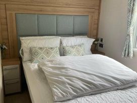 a bedroom with a bed featuring a wooden headboard, pillows, and linen at Quay West Holiday Park - Holiday Accommodation 16905, New Quay
