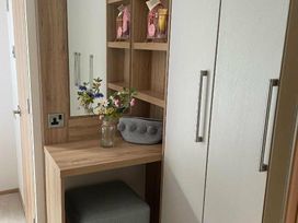 a hallway area with a wooden console table, a vase of flowers, and storage cabinets at Quay West Holiday Park - Holiday Accommodation 16905 in New Quay