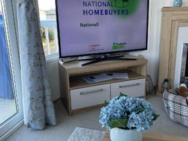 a living room with a television and floral decorations at Quay West Holiday Park - Holiday Accommodation 16905 New Quay