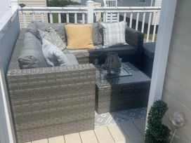 a seating area with a gray sofa and cushions on a deck at Quay West Holiday Park - Holiday Accommodation 16905, New Quay