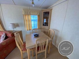 a dining area with a wooden table and chairs beside a cabinet at Meadow Lakes Caravan Hire