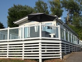 A building with a deck and umbrella at Waterside Bowleaze Cove Holiday Park - Holiday Accommodation 16929 in Weymouth
