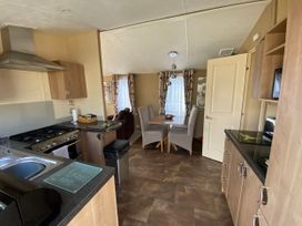 A kitchen with an oven, sink, and dining table at Chesil Beach Holiday Park - Holiday Accommodation 16933, Weymouth
