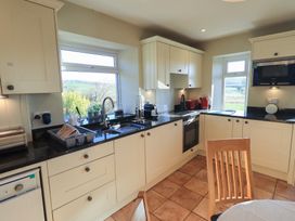 A kitchen with cabinets and appliances at 2 Lupton Hall Cottages in Carnforth